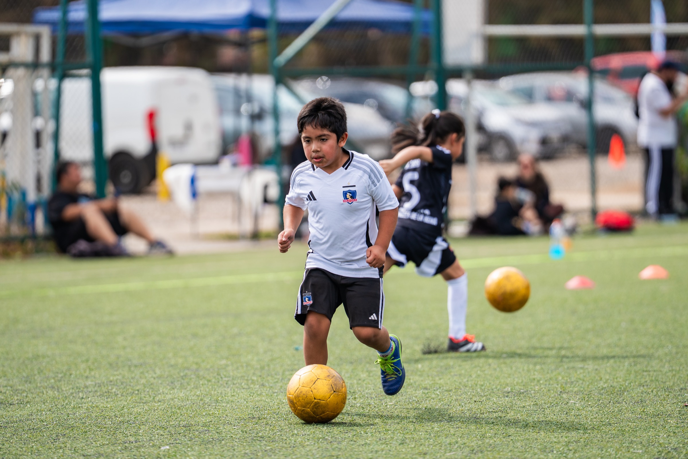 Alumno de las Academias Colo-Colo conduciendo el balón con la camiseta alba